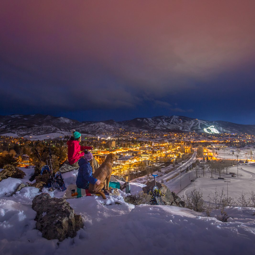 Snowshoeing to top of mountain in Steamboat with dog and picnic - winter town lights